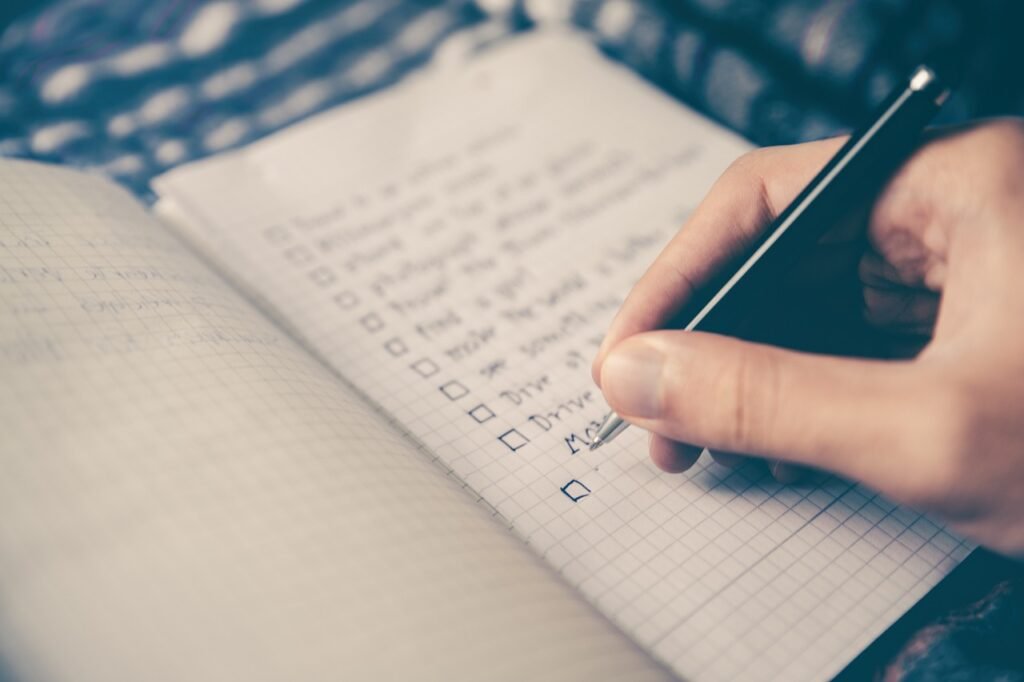 Mão escrevendo metas financeiras em caderno durante planejamento pessoal